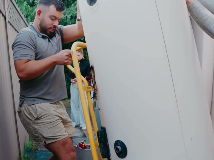 Plumber moving a hot water tank on a trolley