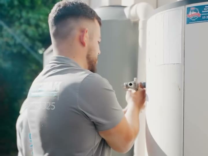 Plumber fitting a valve on a hot water tank